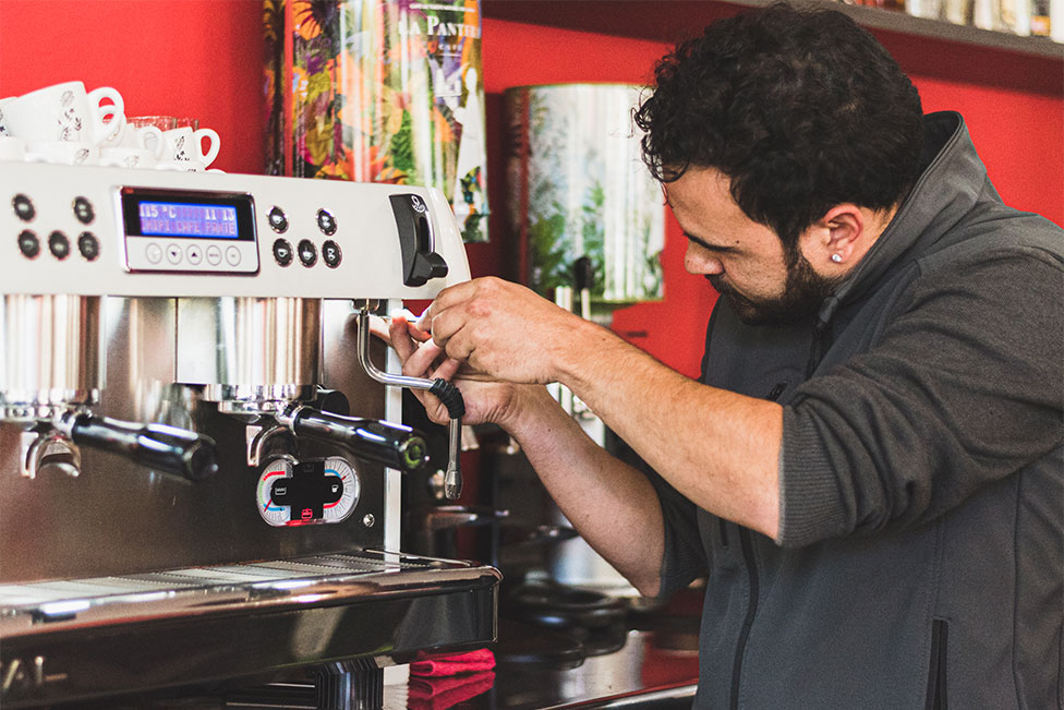 Técnico de Servimatic ofreciendo el servicio de atención técnica y reparando una máquina de café en un bar